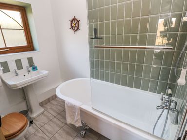 A bathroom with a bathtub with a glass screen and towel a pedestal sink and a toilet with wooden seat at Nant Moel Isaf Farm in Rhydyfro near Pontardawe