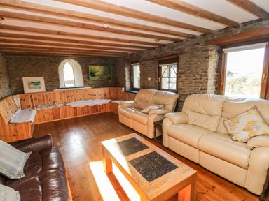 A living room with leather sofas wooden coffee table built in wooden bench and stone walls at Nant Moel Isaf Farm in Rhydyfro near Pontardawe