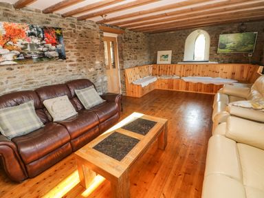 A living room with brown leather sofa beige sofa wooden corner bench and a wooden coffee table at Nant Moel Isaf Farm in Rhydyfro near Pontardawe