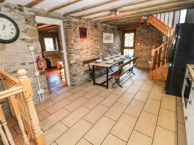 A dining area with a wooden table and benches set with plates and glasses next to stone walls and wooden stairs at Nant Moel Isaf Farm in Rhydyfro near Pontardawe