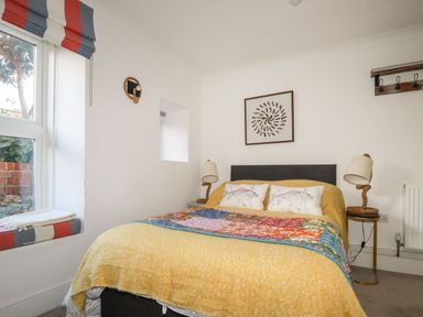A bedroom with a bed yellow blanket and colorful quilt with two fish pillows and two rope lamps at Melvill Lower Deck in Falmouth