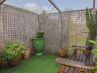 A small enclosed garden area with potted plants and a wooden bench at Melvill Lower Deck in Falmouth