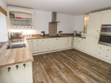 A kitchen with cream cabinets wooden countertops a stainless steel sink and oven at Y Beudy in Crosswell Eglwyswrw near Newport Pembrokeshire