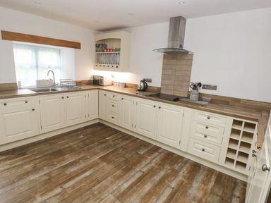 A kitchen with cream cabinets wooden countertops a stainless steel sink and a cooking range at Y Beudy in Crosswell Eglwyswrw near Newport Pembrokeshire