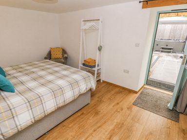 A bedroom with a bed a chair a clothes rack with folded towels and an open door leading outside at Y Beudy in Crosswell Eglwyswrw near Newport Pembrokeshire