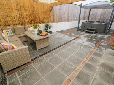 An outdoor seating area with a sofa and table and a hot tub in a covered patio area at Y Beudy Crosswell Eglwyswrw near Newport Pembrokeshire