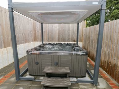 An outdoor hot tub with steps and a cover in a fenced patio area at Y Beudy in Crosswell Eglwyswrw near Newport Pembrokeshire
