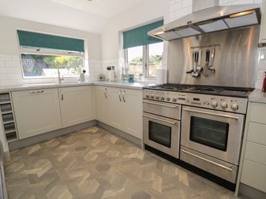 A kitchen with stainless steel oven and range hood and white cabinets at Monarfon in Amlwch