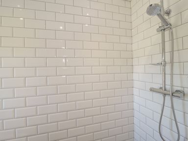 A shower area with white subway tiles and a chrome showerhead at Monarfon in Amlwch