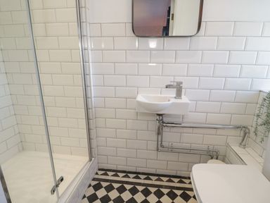 A bathroom with a shower enclosure a small sink a mirror and a toilet at Monarfon in Amlwch