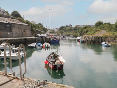 A small harbor with multiple boats on the water and buildings and greenery on either side at Monarfon in Amlwch