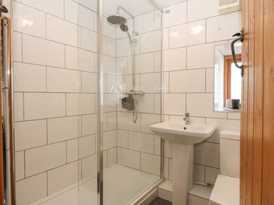 A bathroom with a shower enclosure a pedestal sink a toilet and a window at Ty Gwennol in Llanfaethlu