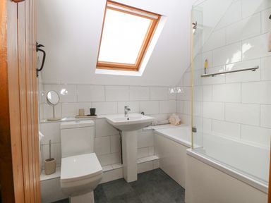 A bathroom with a toilet sink bathtub and skylight window at Ty Gwennol in Llanfaethlu