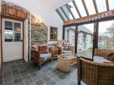 A conservatory with seating and a table at Ty Gwennol in Llanfaethlu