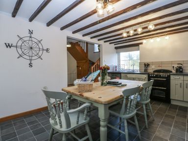 A kitchen with a table and chairs at Ty Gwennol in Llanfaethlu