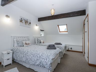 A bedroom with two beds and a window at Ty Gwennol in Llanfaethlu