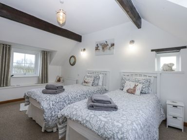 A bedroom with two beds and window at Ty Gwennol in Llanfaethlu