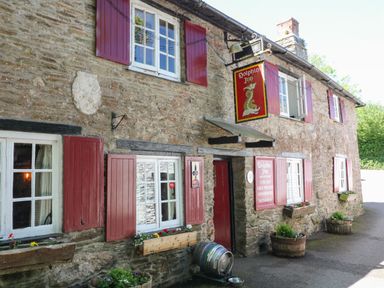 A stone building with red shutters and flower boxes with a sign reading Dolphin Inn at 3 Rock Cottages in Kingston
