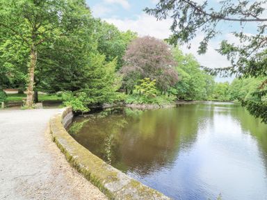 A pathway next to a pond surrounded by trees at East Lodge - Crathes Castle in Crathes Castle near Banchory