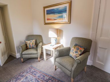 A sitting area with two armchairs and a lamp on a small table between them at East Lodge - Crathes Castle in Crathes Castle near Banchory
