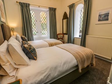 A bedroom with two single beds pillows and throws curtained windows a chair and a wall mirror at East Lodge - Crathes Castle Crathes Castle near Banchory
