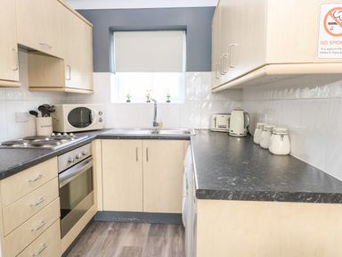 A kitchen with light wood cabinets black countertops a stainless steel oven a microwave sink and small appliances at 91 Waterside Park in Lowestoft