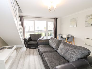 A living room with two sofas a dining table with chairs and a large window at 91 Waterside Park in Lowestoft