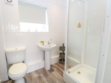 A bathroom with a toilet sink shower and a three-tier basket at 91 Waterside Park in Lowestoft