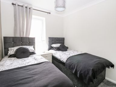 A bedroom with two single beds with dark headboards and bedding at 91 Waterside Park in Lowestoft