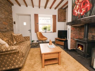 A living room with a patterned sofa wooden coffee table and a wood burning stove at Ascot Cottage Sheriff Hutton near Strensall