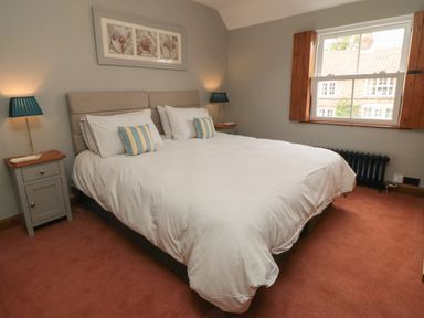 A bedroom with a double bed two bedside tables with lamps a window with wooden shutters and a heater at Ascot Cottage Sheriff Hutton near Strensall