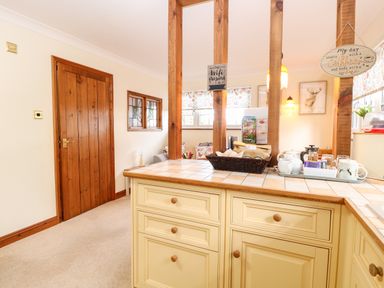 A kitchen counter with cabinets and a basket of items next to tea and coffee supplies at Hunters Lodge in Great Moulton near Long Stratton