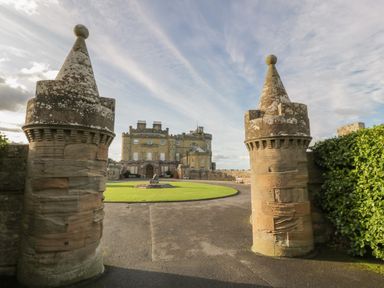 Stone gateway pillars leading to a castle with a circular driveway and lawn at Ardlochan Lodge - Culzean Castle in Maybole