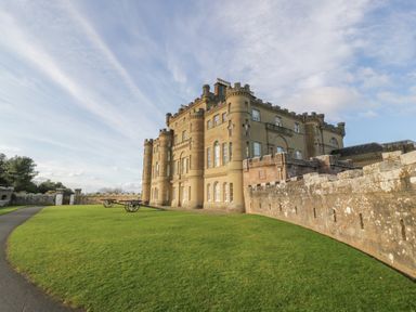 A stone castle with battlements and cannons on a lawn at Ardlochan Lodge - Culzean Castle in Maybole