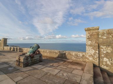 A stone terrace with an old cannon facing the sea under a blue sky at Ardlochan Lodge - Culzean Castle Maybole