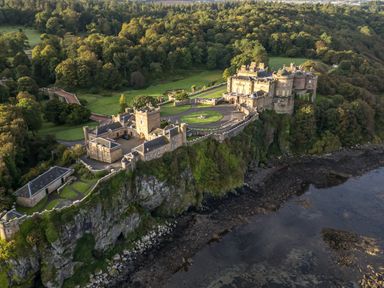 A large castle on a cliff surrounded by trees and overlooking a rocky shoreline at Ardlochan Lodge - Culzean Castle in Maybole