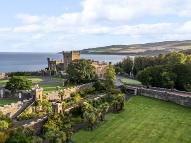 A castle with stone walls and gardens overlooking a large body of water at Ardlochan Lodge - Culzean Castle in Maybole