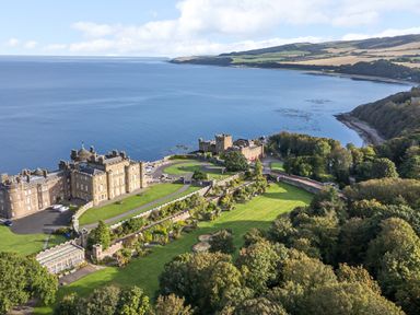 A castle with surrounding gardens and trees near a coastline at Ardlochan Lodge - Culzean Castle in Maybole