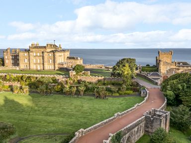 A large historic castle with stone walls and gardens near a body of water at Ardlochan Lodge - Culzean Castle in Maybole