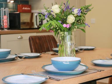 A dining table set with plates and flowers at Ardlochan Lodge - Culzean Castle Maybole