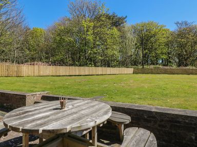 A garden with a wooden table and chairs at Ardlochan Lodge - Culzean Castle in Maybole