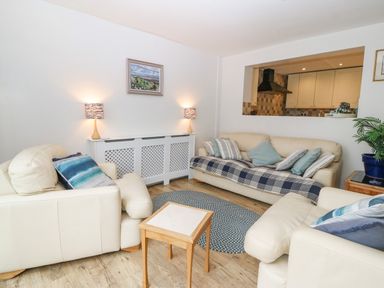 A living room with cream sofas and a small wooden table at Angorfa in Beaumaris