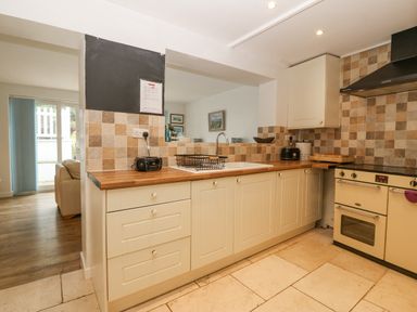 A kitchen with cream cabinets tiled backsplash wooden countertop and cream oven at Angorfa in Beaumaris