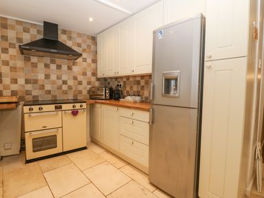 A kitchen with a stove oven range hood refrigerator and cabinets at Angorfa in Beaumaris
