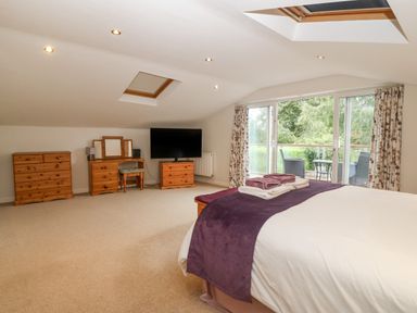 A bedroom with a bed and folded towels vases on a dresser and a television across from a sliding glass door leading to a balcony at Angorfa in Beaumaris