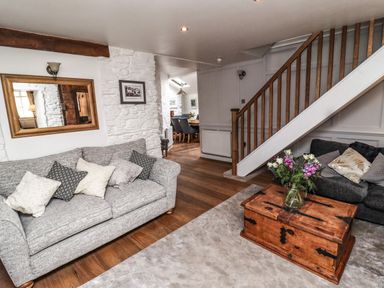 A living room with sofas a wooden chest as coffee table flowers on the table and a staircase at Garretts in Kingsand And Cawsand