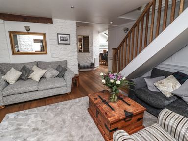 A living room with sofas a wooden chest coffee table flowers on it and wooden staircase at Garretts in Kingsand And Cawsand