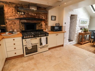 A kitchen with a stove oven microwave wooden countertops and a door leading to another room at Garretts Kingsand And Cawsand