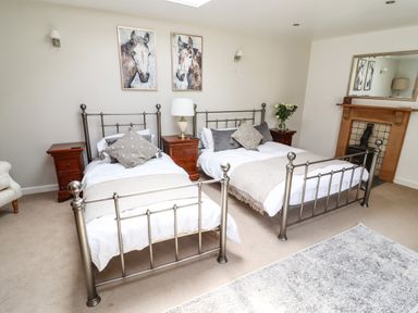A bedroom with two metal frame beds bedside tables a lamp a fireplace and horse paintings at Garretts in Kingsand And Cawsand
