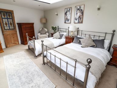 A bedroom with two metal frame beds wooden dressers armchair and paintings of horses at Garretts in Kingsand And Cawsand